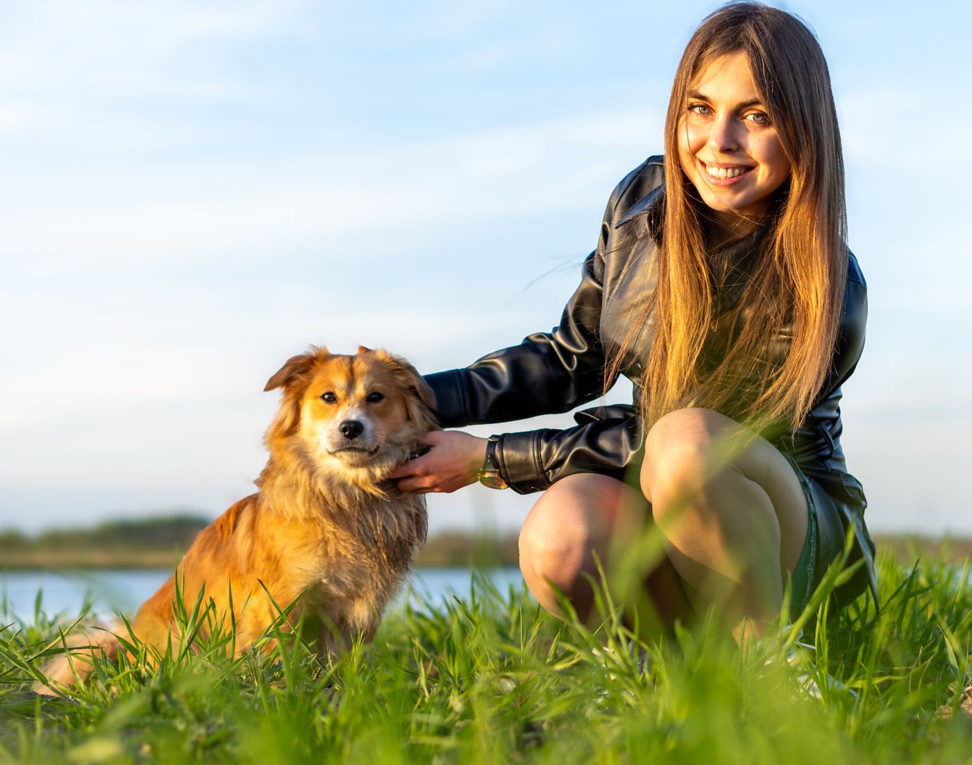 A trainer smiling with her dog outdoors on the grass